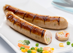 Damhus Veggiegriller, 3000g, gebraten & geschnitten.  Zwei gebratene Bratwürstchen mit Gewürzen auf einem Teller. Ein Würstchen ist im Anschnitt zu sehen und Gemüse erkennbar.