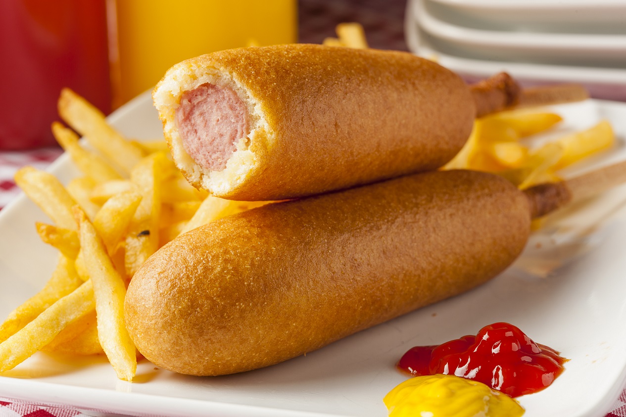 Zwei Bockwürste im Teigmantel. Ein Corn Dog ist angebissen.